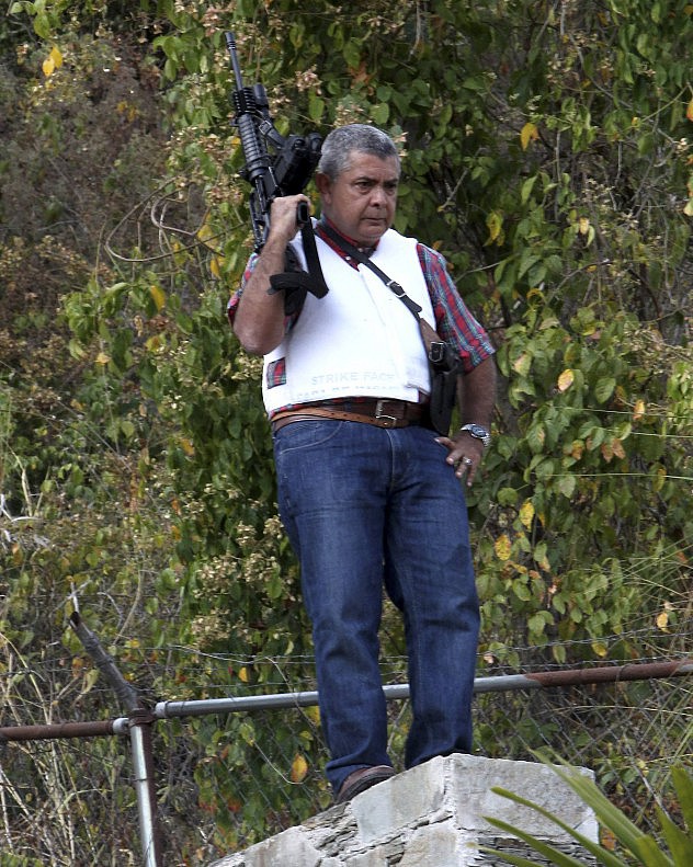 Angel Vivas, a retired army general and anti-Maduro protester, stands in his house with an automatic weapon as he resists be detained in Caracas