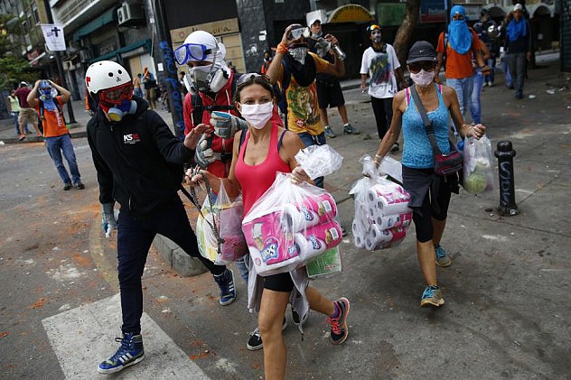 Compradoras de bienes en un supermercado en Chacao huyen de los disturbios protegidas con mascarillas. Opositores dicen escortarlas "por su seguridad". Foto: REUTERS/Jorge Silva/Yahoo