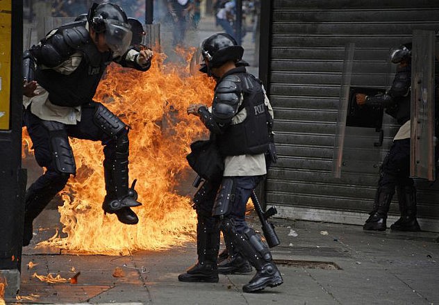 Efectivos de la Policía Nacional Bolivariana son impactados por bombas molotov lanzadas por opositores este jueves en Chacao (Foto: AFP Photo/Juan Barreto)