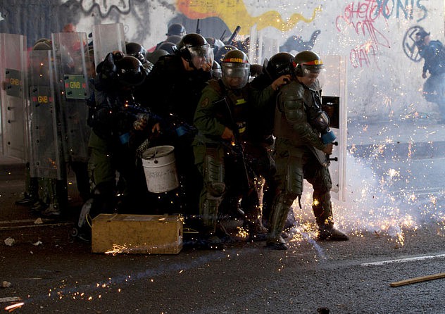 Un grupo de efectivos de la Guardia Nacional Bolivariana se protegen del ataque con cohetones de parte de opositores en Bello Monte. Foto: Fernando Llano, AP
