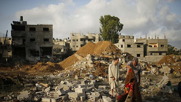 Palestinians stand amongst the rubble of Tayseer Al-Batsh's family house, which police said was destroyed in an Israeli air strike in Gaza City July 13, 2014. The Israeli air strike on the family home of Al-Batsh, Gaza's police chief, killed 18 people on Saturday