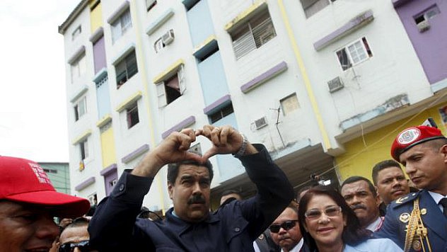 Venezuela's President Nicolas Maduro next to his wife Cilia Flores forms a heart shape with his hands during a visit to the working-class neighbourhood El Chorrilo, which was bombed during the 1989-U.S. invasion, in Panama City
