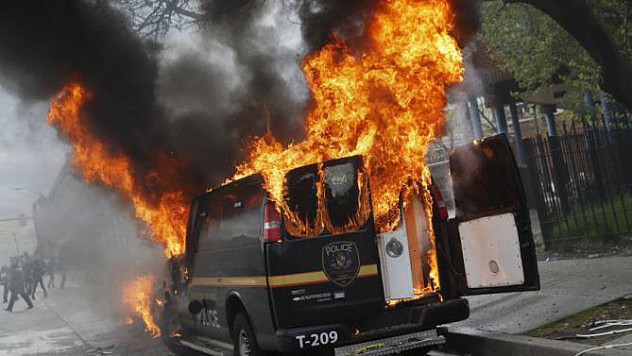 A Baltimore Metropolitan Police transport vehicle burns during clashes in Baltimore, Maryland April 27, 2015. Maryland Governor Larry Hogan declared a state of emergency and activated the National Guard to address the violence in Baltimore, his office said on Monday. Several Baltimore police officers were injured on Monday in violent clashes with young people after the funeral of a black man, Freddie Gray, who died in police custody, and local law enforcement warned of a threat by gangs. REUTERS/Shannon Stapleton