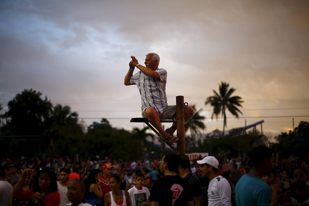 A fan takes a photograph while sitting on a pole before a free outdoor concert by the Rolling Stones at the Ciudad Deportiva de la Habana sports complex in Havana, Cuba March 25, 2016. REUTERS/Ivan Alvarado