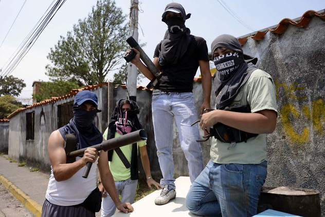 Anti-government activists pose for a picture on a barricade in San Cristobal, Tachira state, on March 6, 2014. A police officer and a civilian died Thursday during clashes in the Venezuelan capital Caracas, bringing to 20 the toll from a month of anti-government demonstrations in the divided country. AFP PHOTO/Leo RAMIREZ