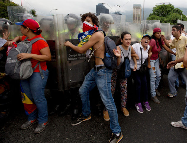 Anti-government demonstrators push against Bolivarian National Police blocking them from reaching the National Electoral Council (CNE) in Caracas, Venezuela, Wednesday, May 11, 2016. The opposition is marching to demand election officials start counting signatures that could lead to a presidential recall vote. (AP Photo/Fernando Llano)