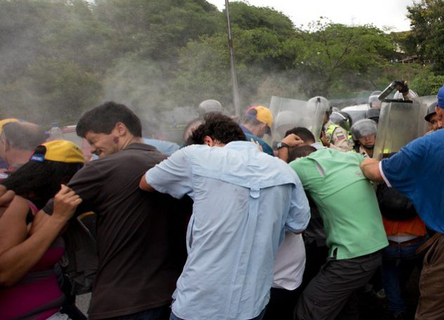 Venezuelans react to the effects of pepper gas after riot police fired the gas to repel marchers protesting against the government, in Caracas, Venezuela, Wednesday, May 11, 2016. Thousands are marching against the country's socialist administration, demanding that elections officials start counting signatures that could lead to a presidential recall vote. On Wednesday, law enforcement cordoned off the electoral building opposition leaders had planned to march to. Opposition leader Henrique Capriles is pictured in baseball cap, back center. (AP Photo/Fernando Llano)