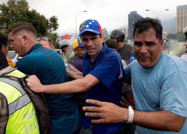 Opposition leader Henrique Capriles, center, reacts to the effects of pepper gas as he is led away by his bodyguards after soldiers fired the gas to repel marchers protesting against the government, in Caracas, Venezuela, Wednesday, May 11, 2016. (AP Photo/Fernando Llano)Thousands of Venezuelans are marching against the country's socialist administration, demanding that elections officials start counting signatures that could lead to a presidential recall vote. (AP Photo/Fernando Llano)