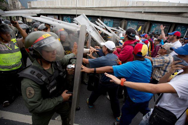 Anti-government demonstrators push against Bolivarian National Guard soldiers blocking their march to the National Electoral Council (CNE) in Caracas, Venezuela, Wednesday, May 11, 2016. The opposition is marching to demand election officials start counting signatures that could lead to a presidential recall vote. (AP Photo/Fernando Llano)